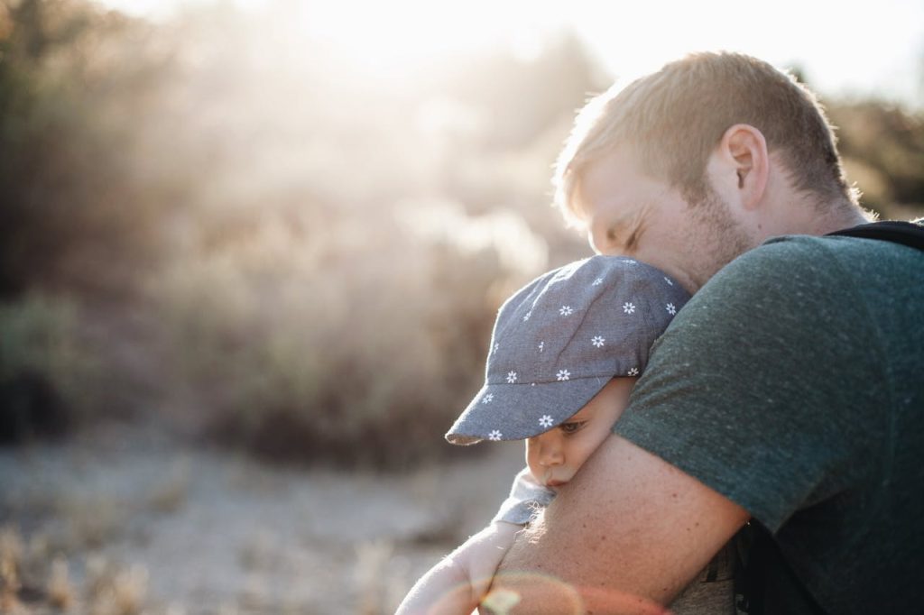 Father holding his young child in a tender embrace, symbolizing healing and breaking the cycle of growing up without a father.