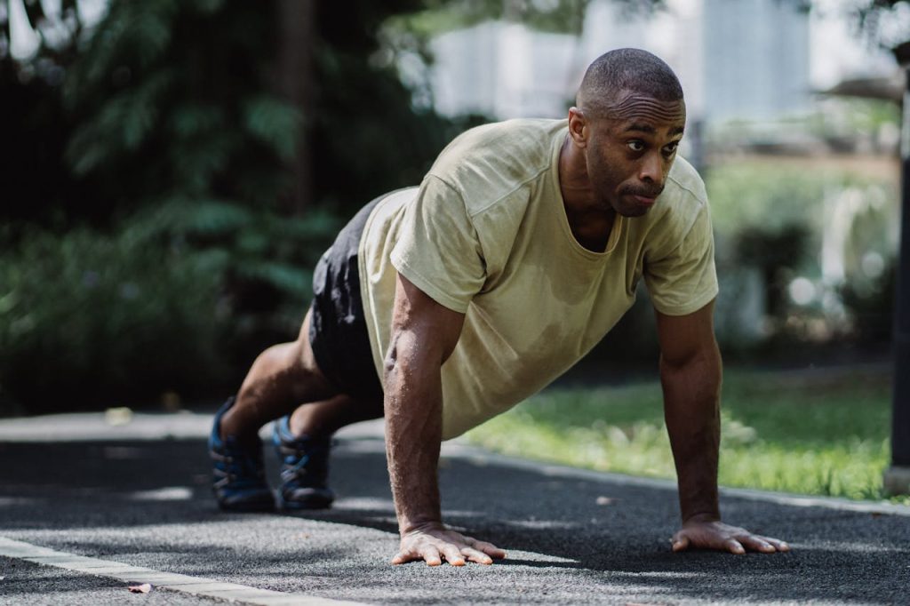 Man exercising outdoors in a plank position, illustrating healthy coping strategies for anxiety in men through physical activity.