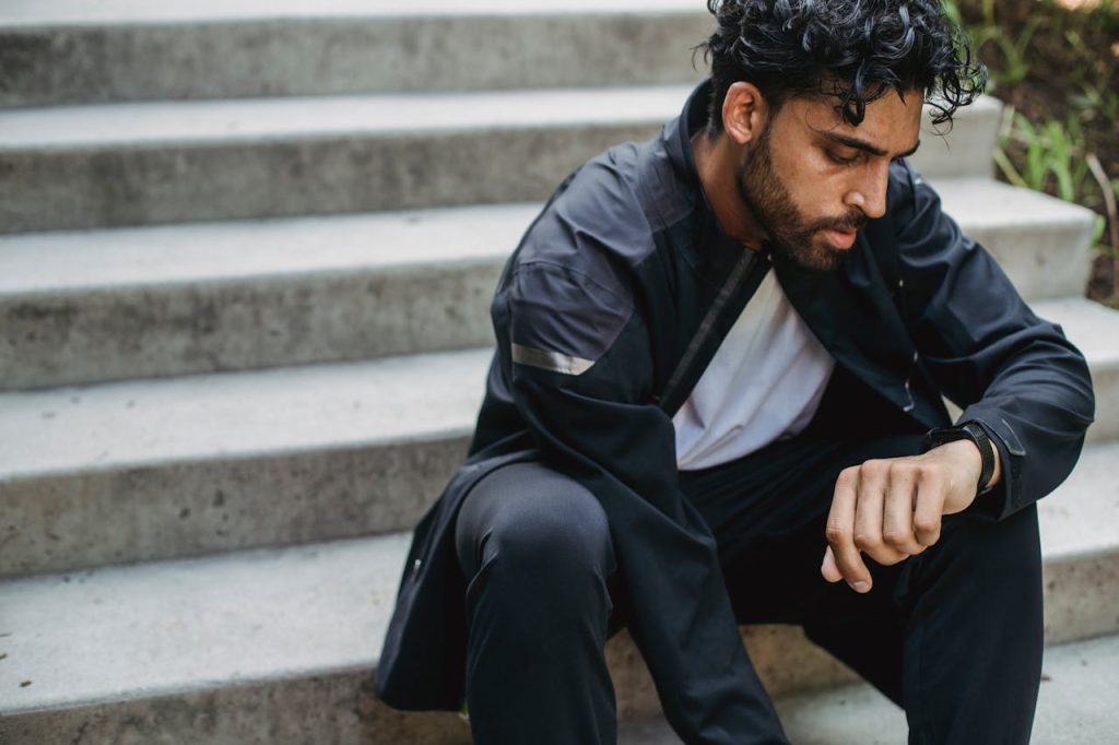 Man sitting alone on concrete steps with head lowered, reflecting emotional isolation and the internal struggle associated with growing up without a father.