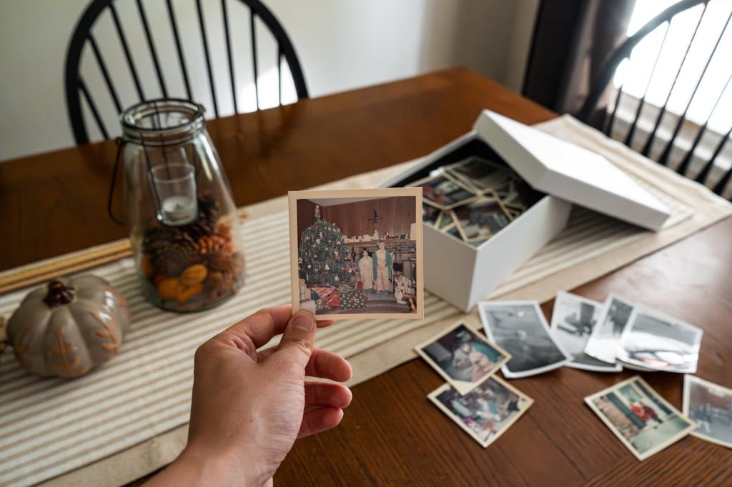 Person holding an old family photograph, reflecting on childhood dynamics and childhood’s impact on love life.