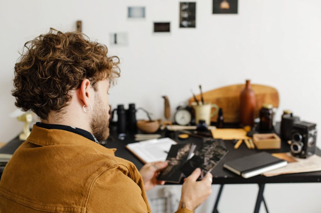 Young man studying an old photograph at a desk, reflecting on the past and the emotional effects of growing up without a father.