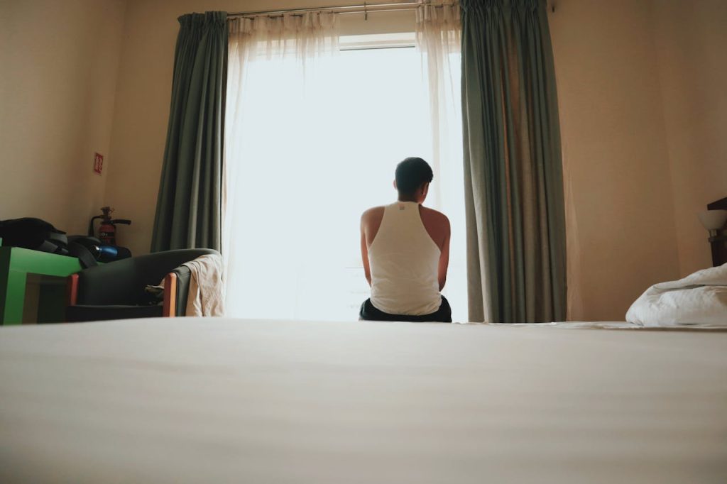 Man sitting alone by a window in quiet contemplation, representing vulnerability, emotional introspection, and intimacy beyond sex.