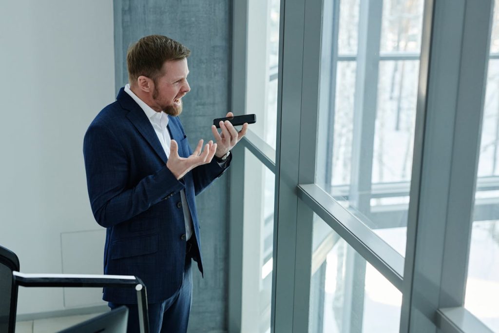 Man in a suit speaking tensely on the phone, displaying anger and frustration as common outward expressions of anxiety in men.