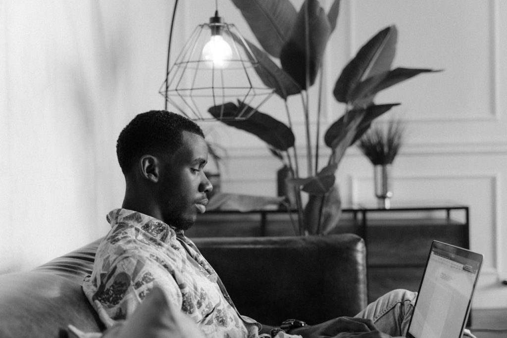 Man working attentively on a laptop in a calm interior, symbolizing action-oriented masculine energy expressed through focus and purpose.