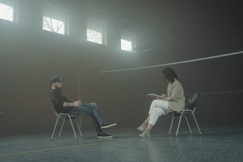 Man in psychotherapy session, sitting across from a therapist, representing healing after growing up without a father.