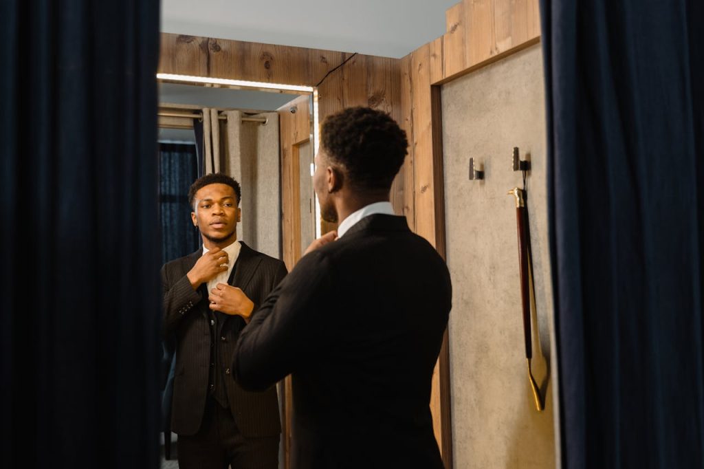 A man adjusting his jacket while looking calmly into a mirror, conveying self-respect, confidence, and personal boundaries.