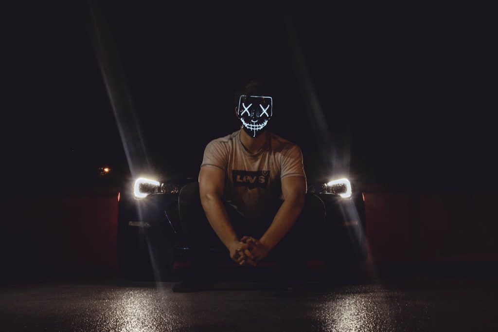 Man wearing a glowing mask at night, symbolizing hiding the authentic self behind a masculine facade shaped by toxic masculinity.