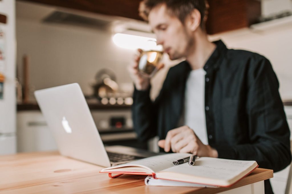 Man journaling alone at a kitchen table in morning light, practicing self-reflection and overcoming the fear of being alone.