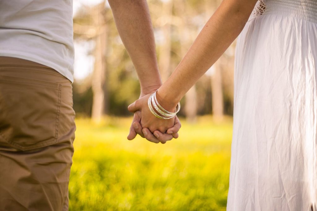 A couple holding hands outdoors, symbolizing balance and harmony between masculine vs feminine energy through mutual presence and connection.