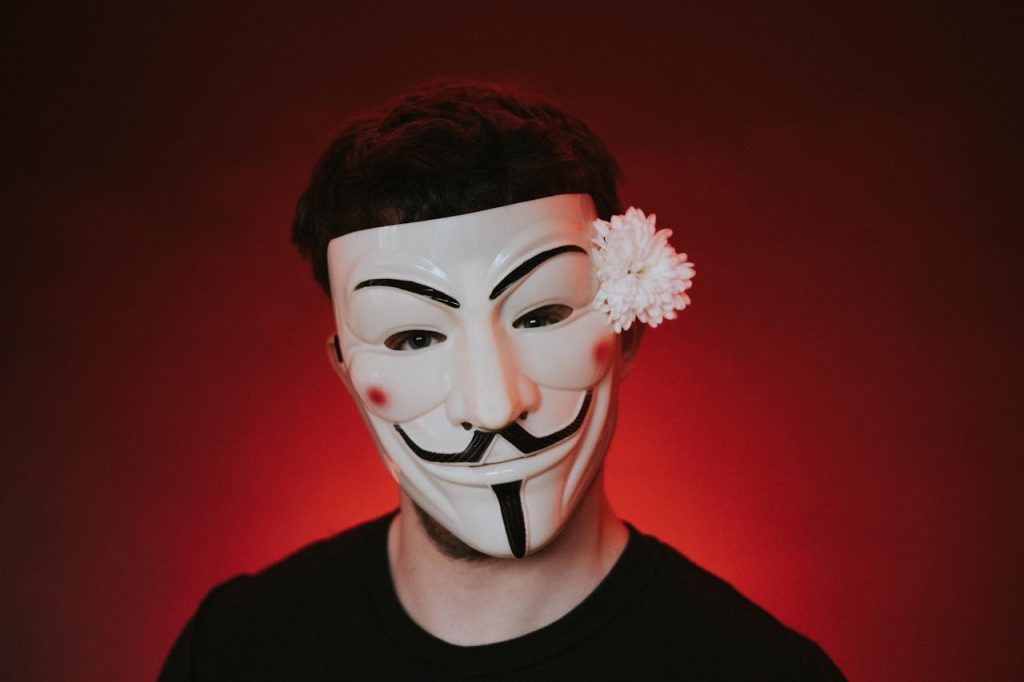 Man wearing a theatrical mask against a red background, symbolizing the emotional concealment involved in overcoming shame as a man.