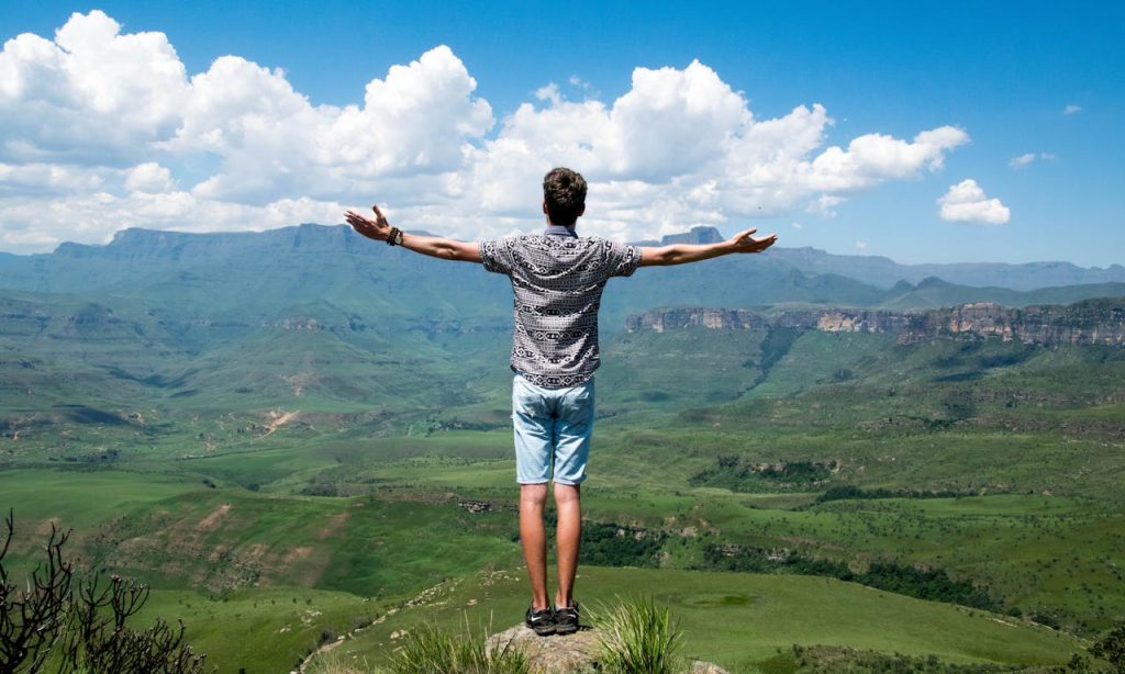 A man standing on a mountain with arms open toward the horizon, illustrating finding inner peace through perspective, calm, and emotional release.