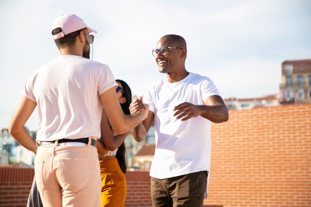 Two men laughing and greeting each other outdoors, illustrating redefining success for men through authentic friendship and meaningful connection.
