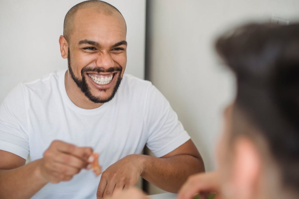 A man laughing naturally during a relaxed conversation, representing authenticity over conformity and genuine self-acceptance.
