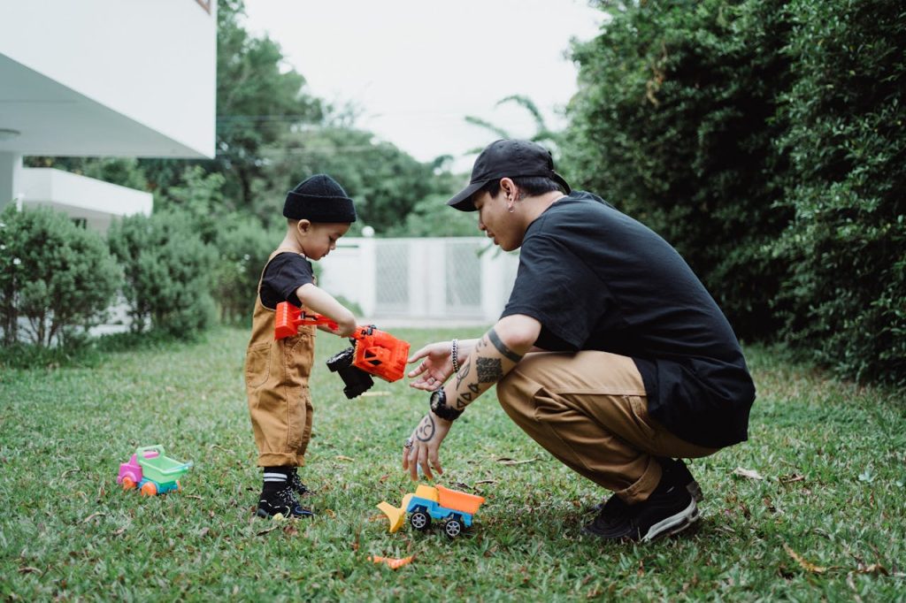 A father crouching beside his young son while playing outdoors, illustrating secure attachment and healthy parent-child bonding that helps prevent the intergenerational transmission of trauma in men.