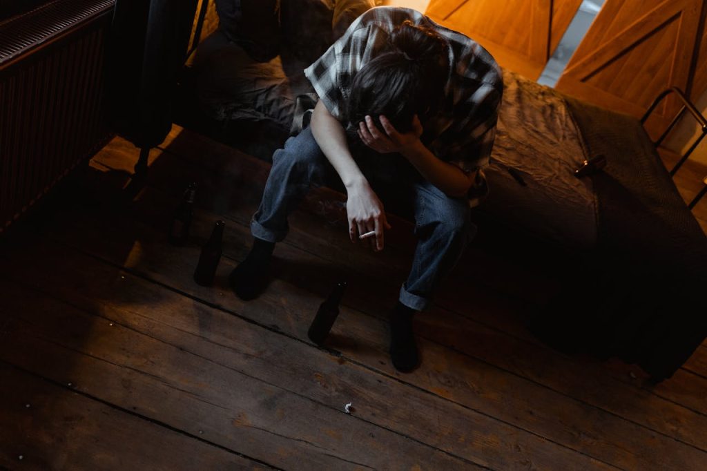 A man sitting on the edge of his bed with his head lowered, appearing exhausted and withdrawn, illustrating the quiet and hidden signs of depression in men.